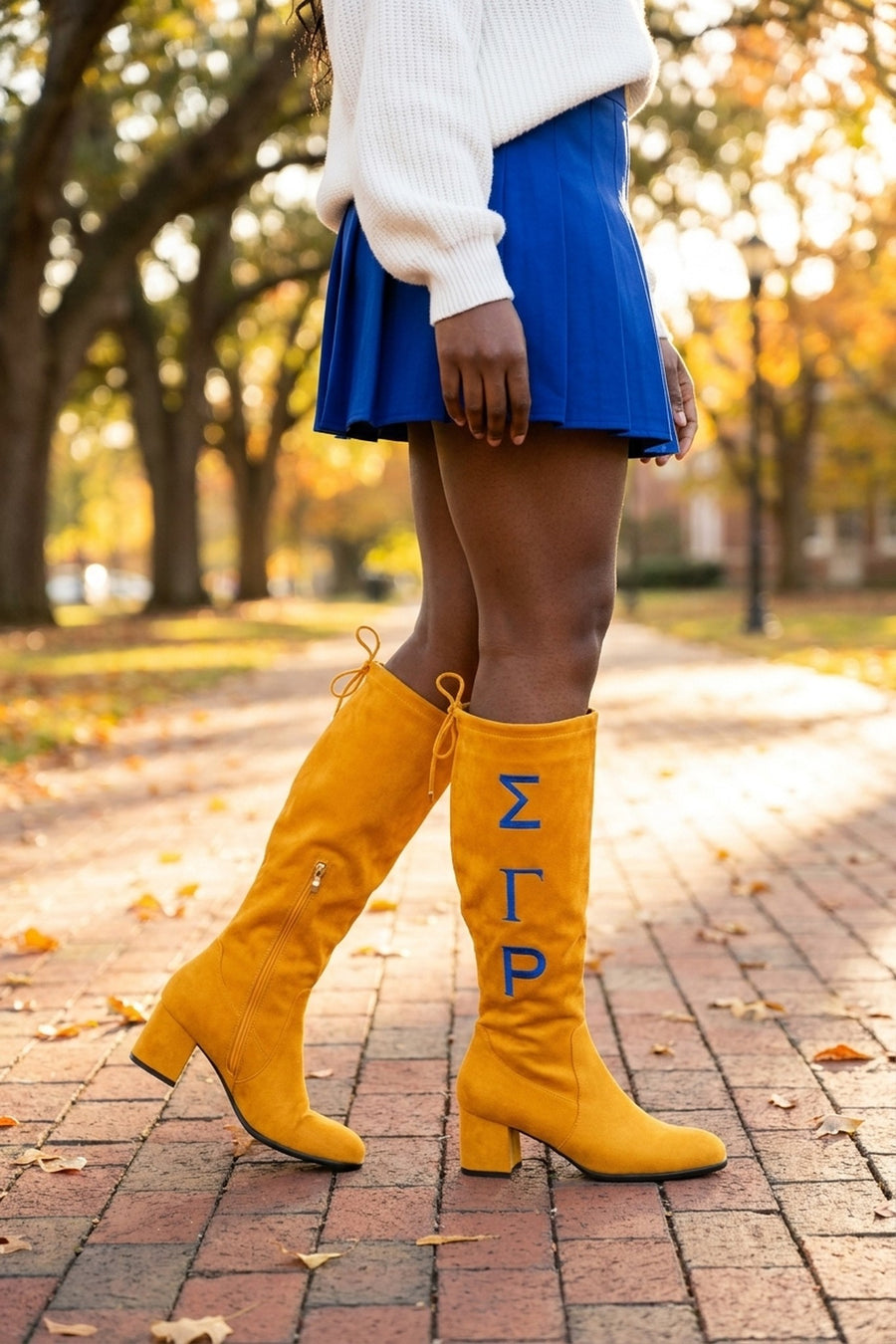 Sigma Gamma Rho Knee-High Boots in gold, on a campus walkway